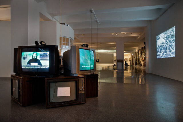 Ausstellungsansicht „Whistleblower & Vigilanten. Figuren des digitalen Widerstands“ im Vordergrund Videos der Gruppe Anonymous