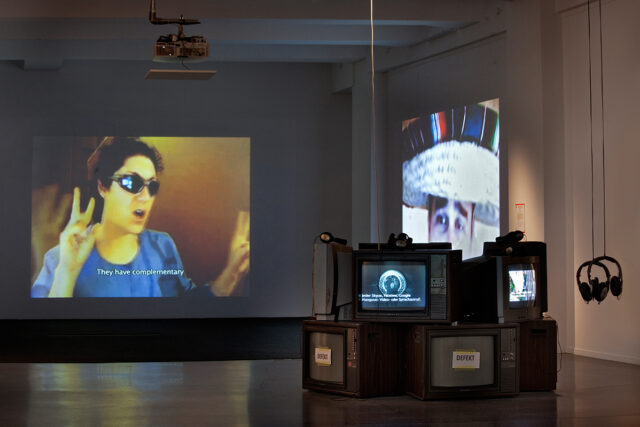 Ausstellungsansicht „Whistleblower & Vigilanten. Figuren des digitalen Widerstands“ Laufzeit: 09.04.2016 - 14.08.2016 im HMKV im Dortmunder U. Im Vordergrund Videos der Gruppe Anonymous, im Hintergrund die Videoarbeiten „RIP in Pieces America“ und „Pieces and Love All to Hell“ von Dominic Gagnon